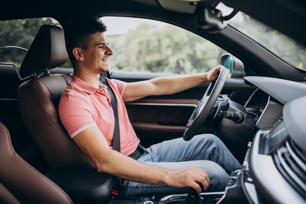 a man sitting inside the car driving the steer wheel