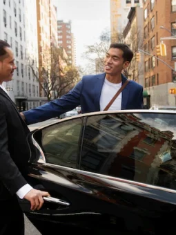 an image of a chauffeur opening the door for a passenger siting inside